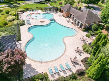 An aerial view of a resort style pool with chairs and a building